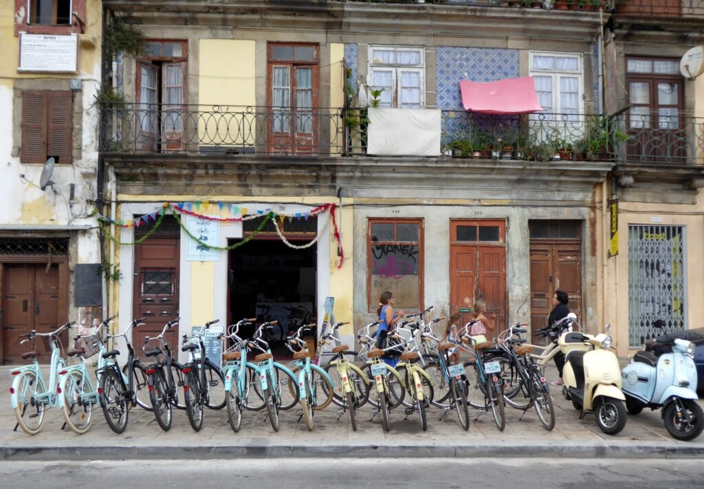 Row of bicycles parked along a bustling street in downtown Porto, with historic buildings in the background.