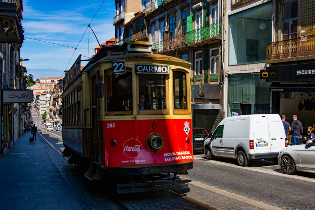 A vintage yellow tram ascends a steep cobblestone street in Porto, surrounded by traditional Portuguese architecture.