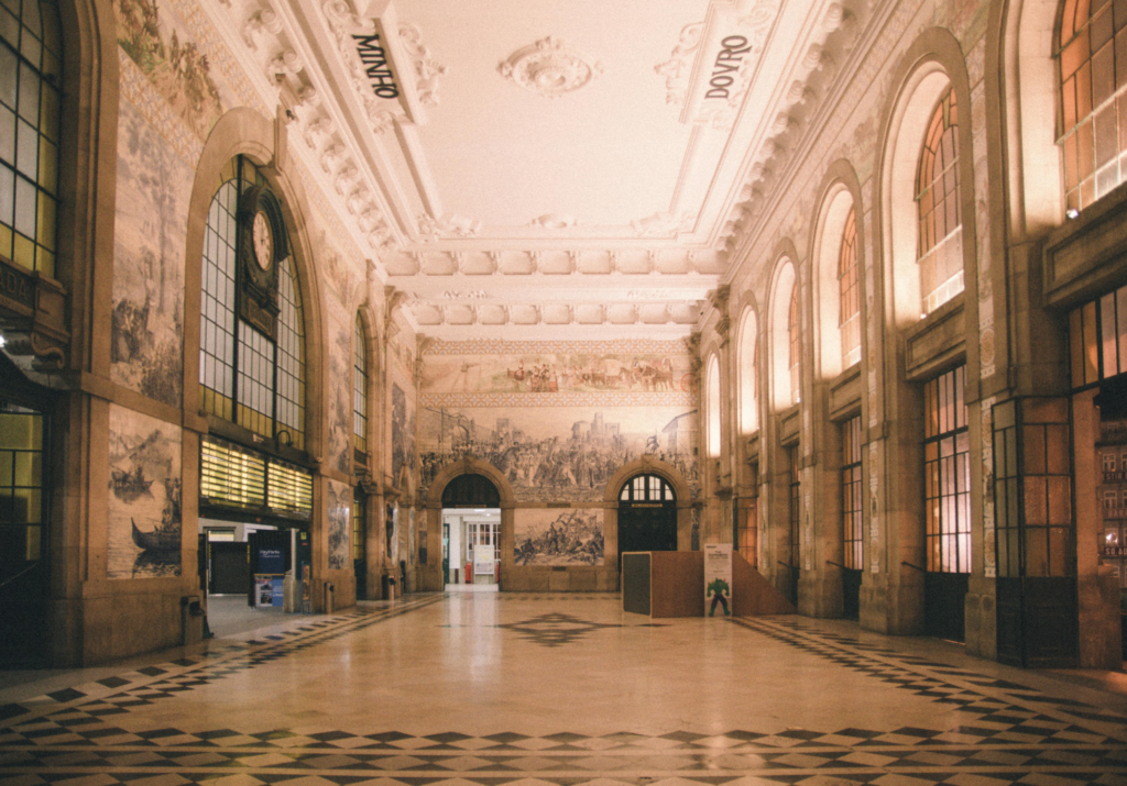 Interior view of São Bento Hall in Porto, featuring its ornate, azulejo-tiled walls depicting historical scenes.