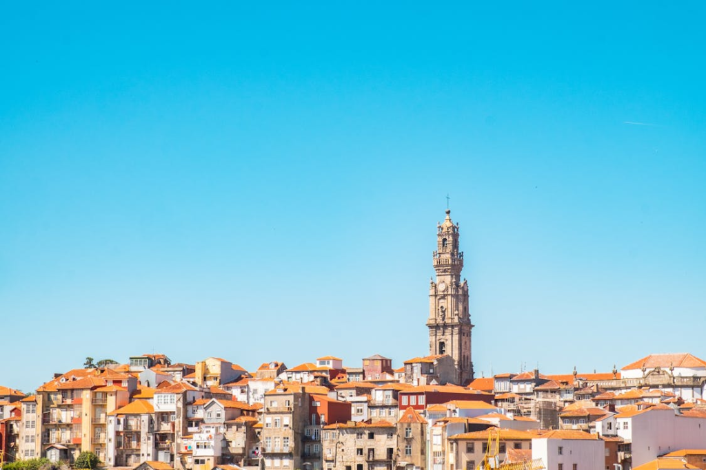 Scenic view of traditional Porto houses with the iconic Torre dos Clérigos visible in the distance under a clear sky.